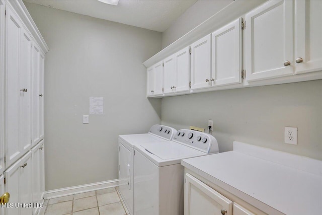 washroom with light tile patterned flooring, washing machine and dryer, and cabinets