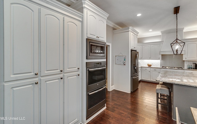 kitchen featuring light stone counters, pendant lighting, stainless steel appliances, tasteful backsplash, and white cabinets