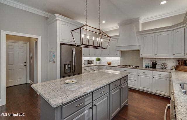 kitchen with dark wood-style flooring, tasteful backsplash, custom range hood, gray cabinetry, and appliances with stainless steel finishes