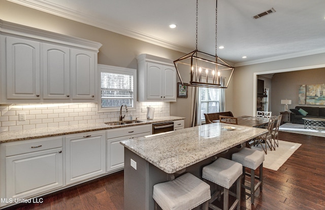 kitchen with light stone countertops, visible vents, decorative backsplash, and a sink