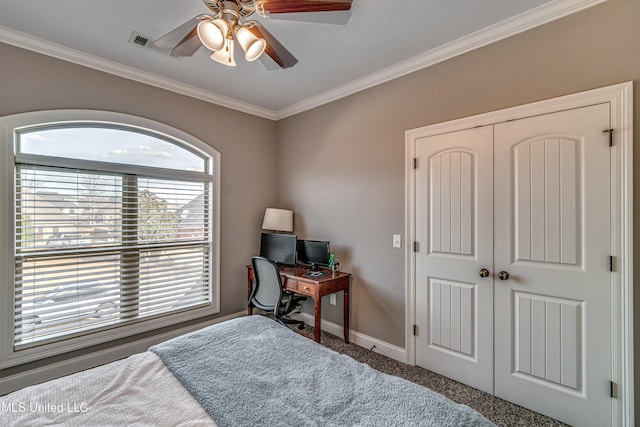 carpeted bedroom with ceiling fan, a closet, baseboards, and crown molding