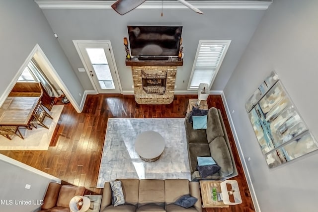 living area featuring wood-type flooring, a fireplace, baseboards, and ornamental molding