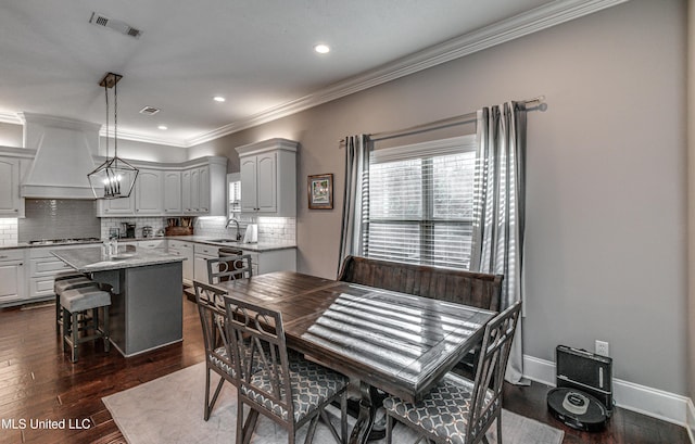 dining room featuring baseboards, visible vents, dark wood-style floors, crown molding, and a chandelier