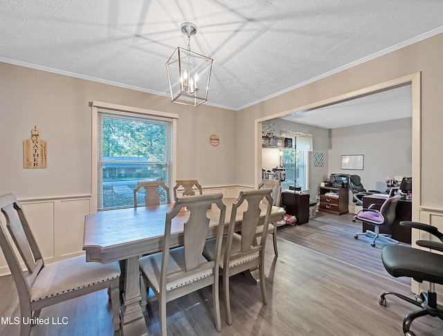 dining room with a notable chandelier, crown molding, a textured ceiling, and wood finished floors