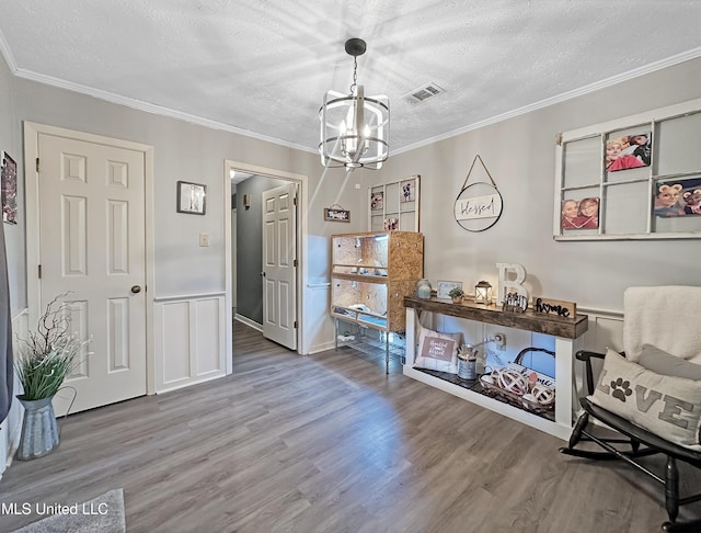 sitting room with a textured ceiling, ornamental molding, and wood finished floors