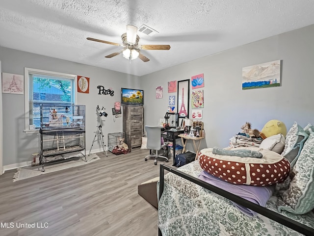 bedroom with visible vents, light wood-style floors, ceiling fan, a textured ceiling, and baseboards