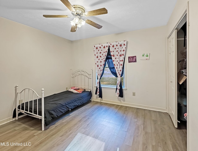 bedroom featuring a textured ceiling, wood finished floors, a ceiling fan, and baseboards