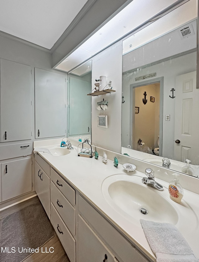 bathroom with visible vents, a sink, toilet, and double vanity