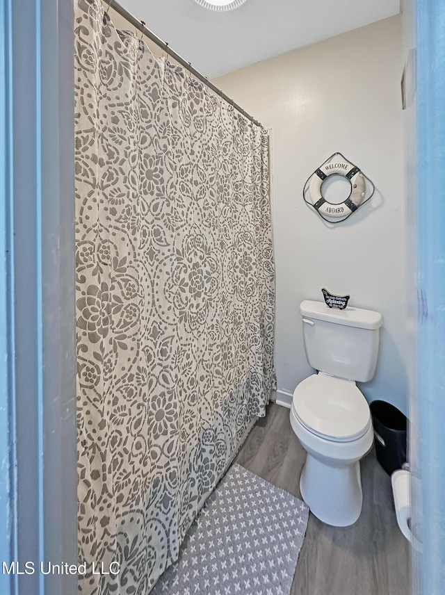 full bathroom with baseboards, wood finished floors, toilet, and a shower with curtain