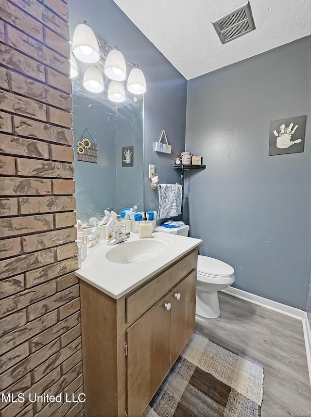 bathroom featuring visible vents, toilet, wood finished floors, a textured ceiling, and vanity