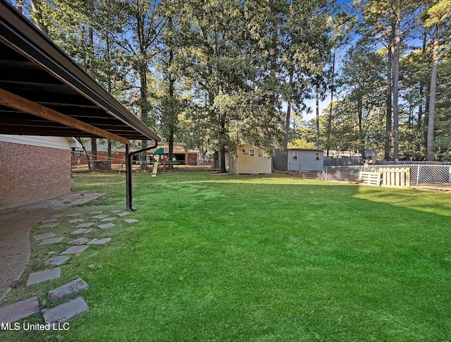 view of yard featuring an outbuilding, a playground, fence, and a shed