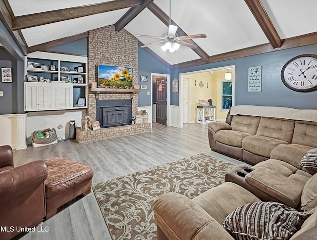 living room with a fireplace, wood finished floors, a ceiling fan, built in features, and wainscoting