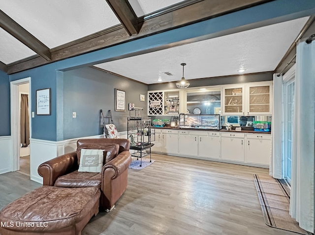 kitchen with light wood-type flooring, ornamental molding, dark countertops, and white cabinetry