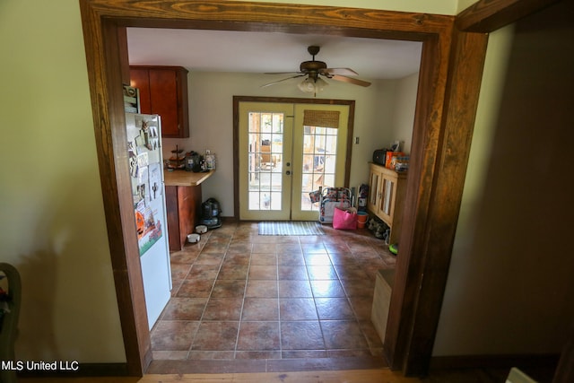 doorway featuring french doors, dark tile patterned floors, and ceiling fan