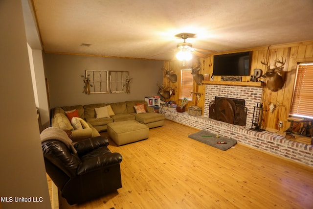 living room with a fireplace, crown molding, light wood-type flooring, a textured ceiling, and ceiling fan