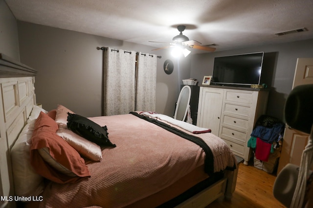 bedroom with ceiling fan, hardwood / wood-style flooring, and a textured ceiling
