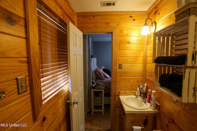 bathroom with vanity, wood walls, and a textured ceiling