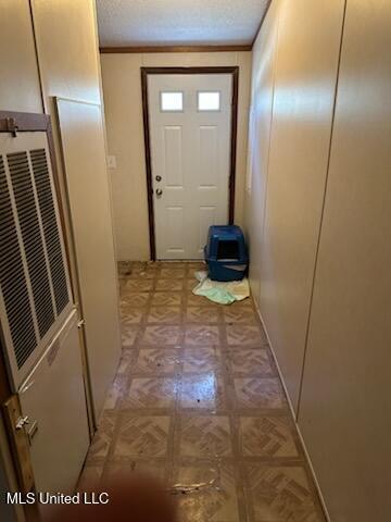 doorway to outside with light floors and a textured ceiling