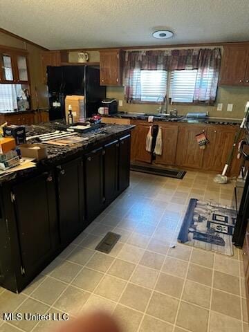kitchen featuring freestanding refrigerator, dark countertops, a textured ceiling, and a sink