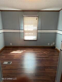 spare room with wood finished floors, visible vents, and baseboards
