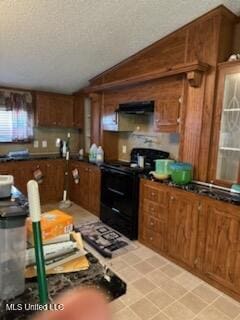 kitchen with black electric range oven, dark countertops, a textured ceiling, brown cabinetry, and ventilation hood