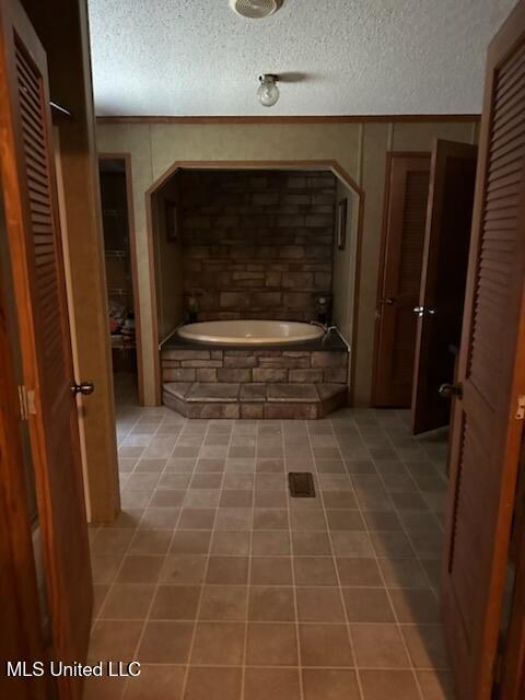 bathroom featuring tile patterned flooring, tiled bath, a textured ceiling, and a closet