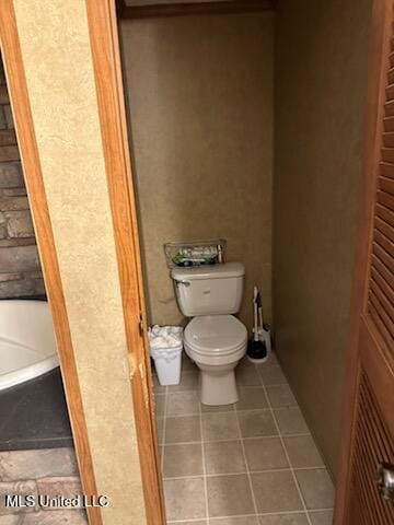 full bath featuring tile patterned floors, a bathtub, and toilet
