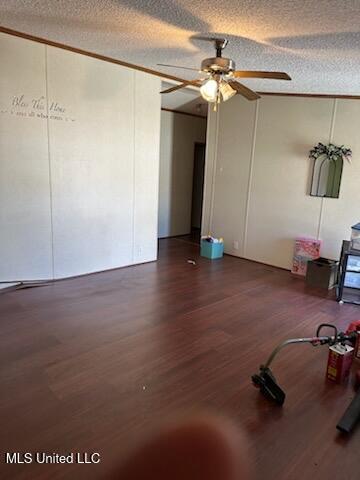 unfurnished living room with ornamental molding, a ceiling fan, wood finished floors, and a textured ceiling
