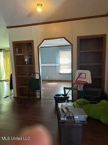 living area featuring wood finished floors, built in features, a textured ceiling, and ornamental molding