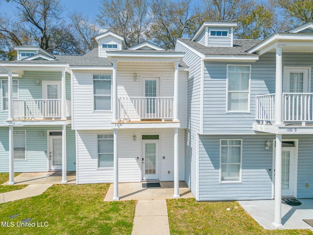 multi unit property with a patio, a front lawn, and a shingled roof