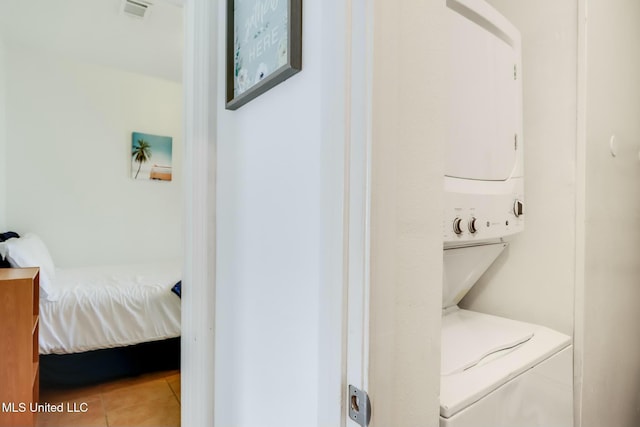 laundry area with laundry area, stacked washer / dryer, and light tile patterned floors