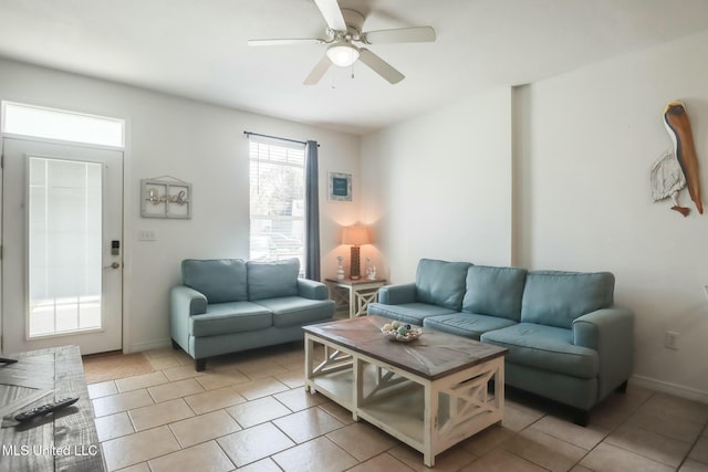 living area featuring light tile patterned floors, baseboards, and ceiling fan