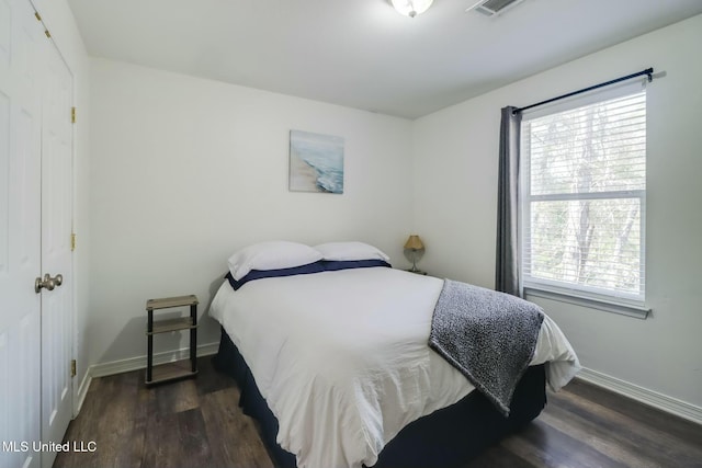 bedroom featuring multiple windows, dark wood-type flooring, and baseboards