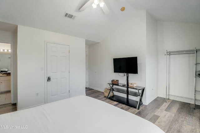 bedroom with visible vents, lofted ceiling, baseboards, and wood finished floors