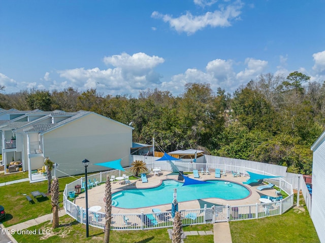 community pool with a patio area, a yard, and a fenced backyard