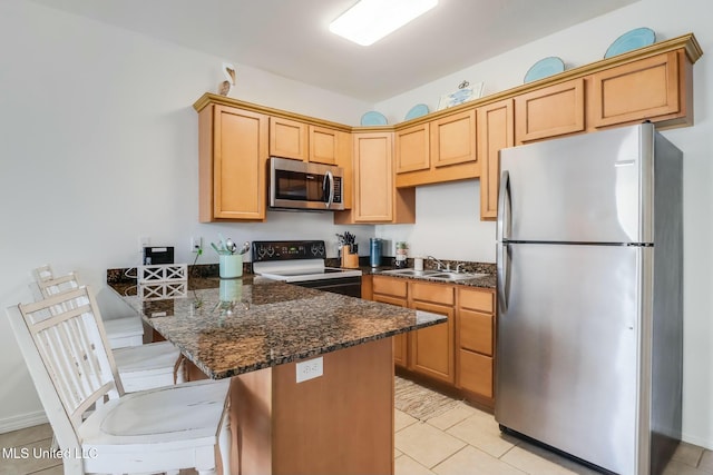 kitchen with a breakfast bar, a peninsula, light tile patterned flooring, stainless steel appliances, and a sink