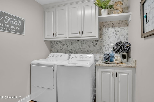 clothes washing area with washing machine and dryer and cabinets