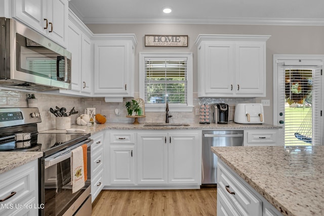 kitchen featuring crown molding, white cabinets, stainless steel appliances, and sink