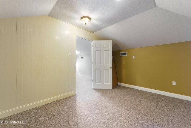 additional living space with lofted ceiling, carpet floors, and a textured ceiling