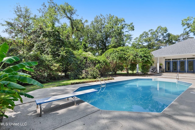 view of swimming pool featuring a diving board and a patio area