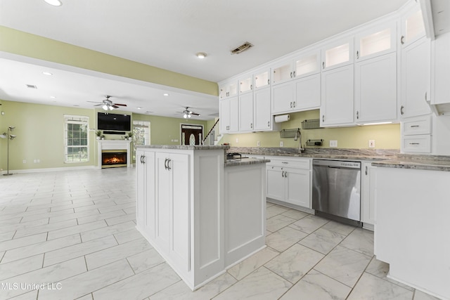 kitchen with white cabinetry, dishwasher, a center island, ceiling fan, and light stone countertops