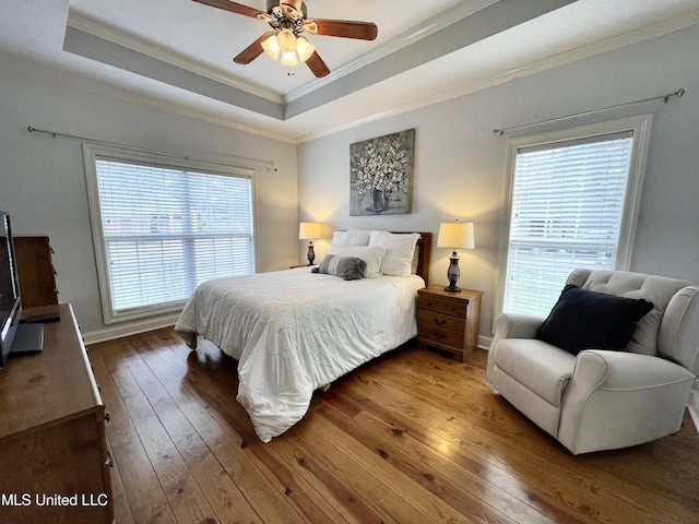 bedroom with a raised ceiling, ornamental molding, hardwood / wood-style floors, and ceiling fan