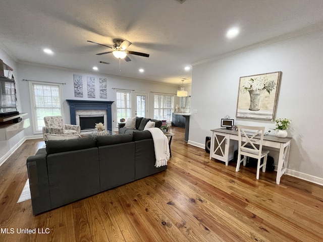 living room featuring hardwood / wood-style flooring, ceiling fan, crown molding, and a textured ceiling