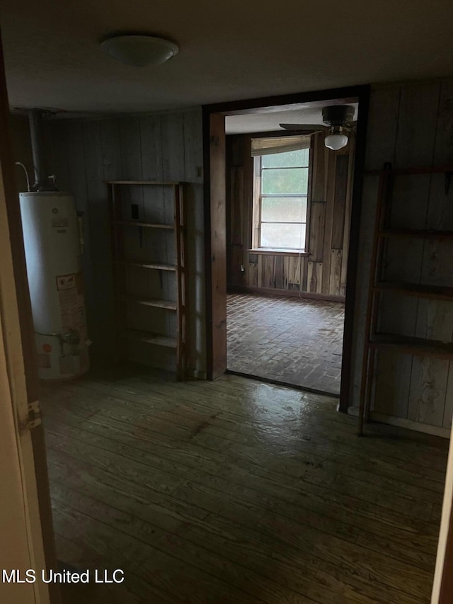 hallway with gas water heater, wood-type flooring, and wooden walls