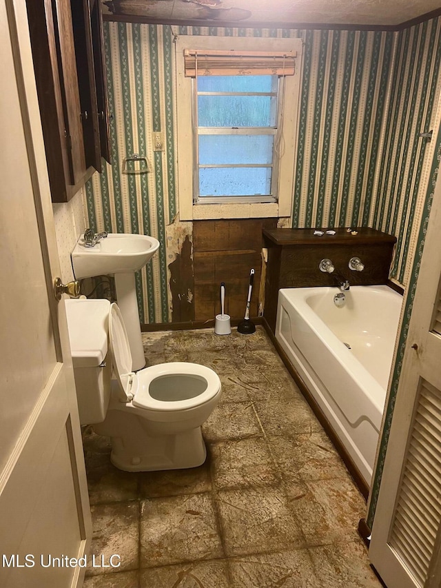 full bathroom featuring wallpapered walls, toilet, and a bath