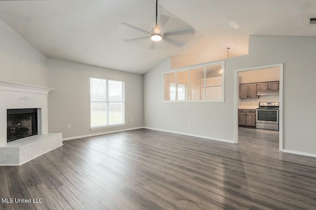 unfurnished living room featuring vaulted ceiling, a fireplace, a textured ceiling, and dark wood-style flooring