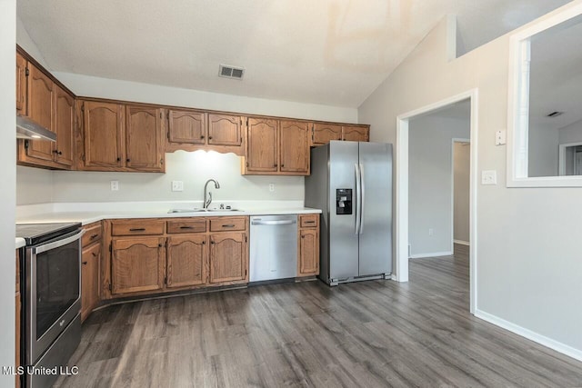 kitchen featuring dark wood finished floors, appliances with stainless steel finishes, light countertops, under cabinet range hood, and a sink