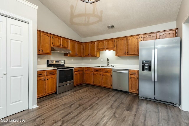 kitchen with stainless steel appliances, brown cabinetry, a sink, and under cabinet range hood