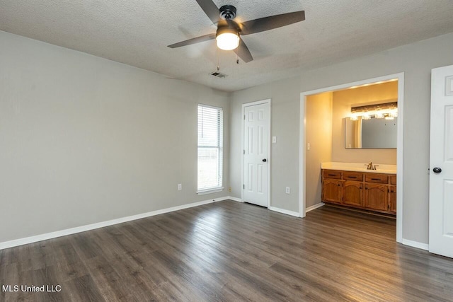 unfurnished bedroom featuring dark wood-type flooring, visible vents, a textured ceiling, and baseboards