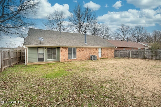 rear view of house with cooling unit, a fenced backyard, brick siding, a shingled roof, and a yard